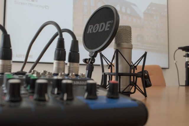 Mischer mit einer Audio-Mixing-Oberfläche neben einem Studio-Mikrofonen