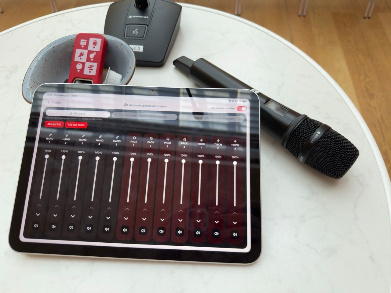Tablet mit einer Audio-Mixing Oberfläche neben zwei Mikrofonen