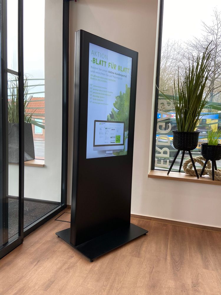 Freistehende schwarze Info-Stele im Hochformat am Fenster des Kundencenters mit einer Aktion zum Online-Kundenportal