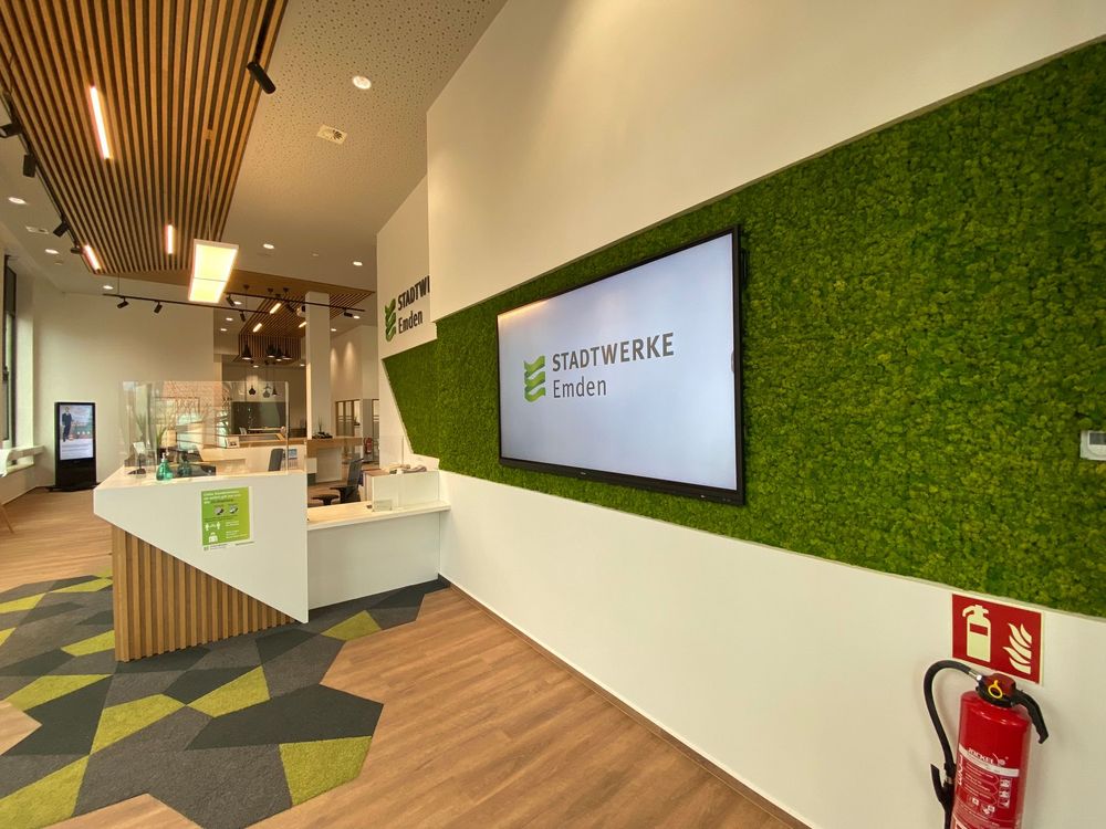 Blick vom Empfang auf ein Wanddisplay mit Stadtwerke-Logo in der Mooswand